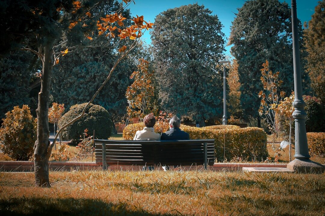 Mature Turkish couple sitting on a bench in a park smiling and talking